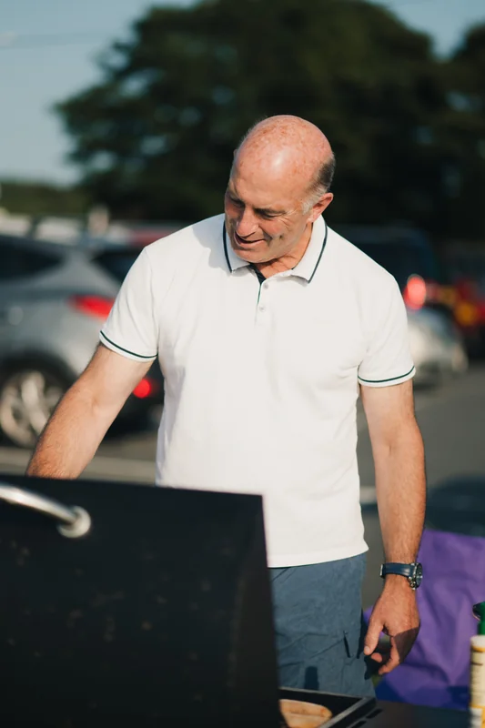 a man grilling on a bbq in a car park