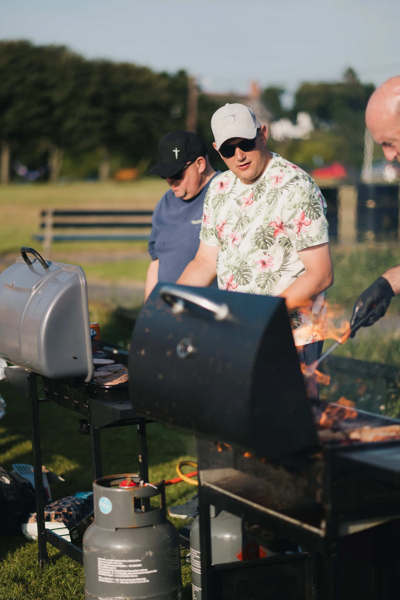 a group of men preparing food on a barbecue grill