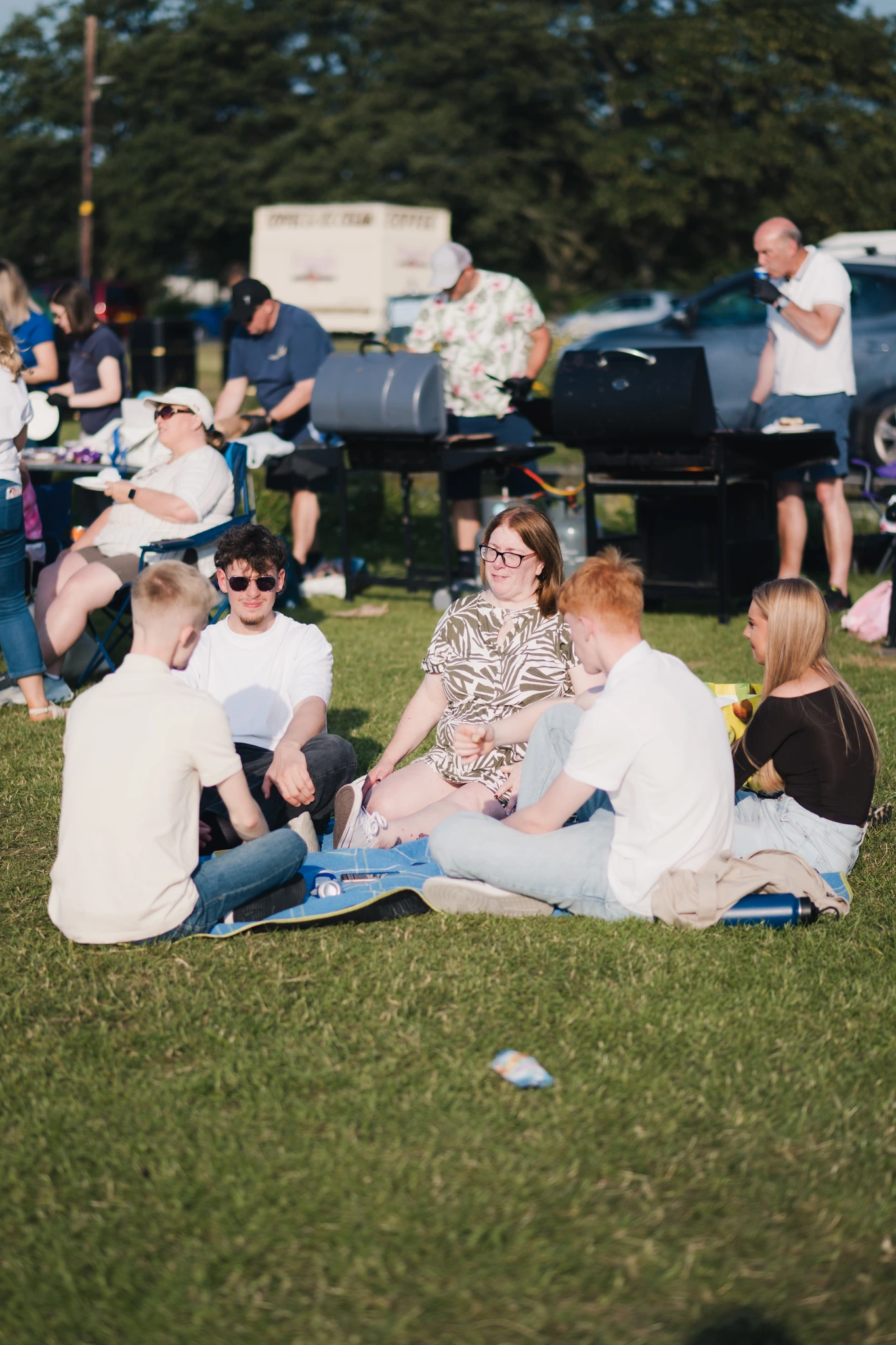 a group of people sitting on the grass at a festival