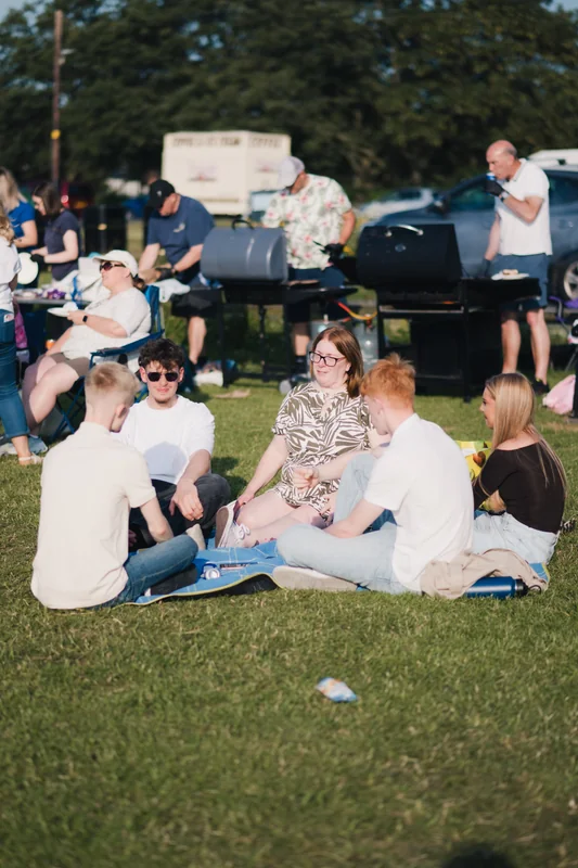 a group of people sitting on the grass at a festival