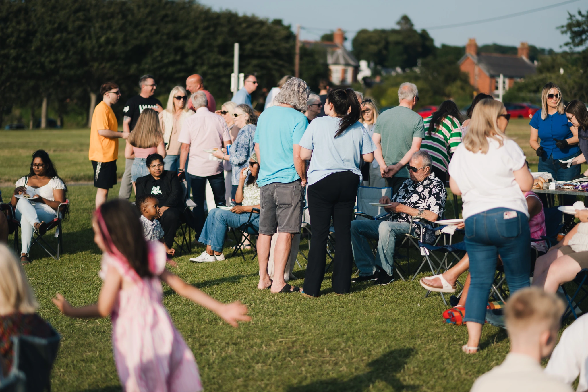 a crowd of people sitting on chairs in a grassy field