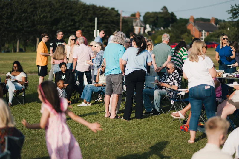 a crowd of people sitting on chairs in a grassy field