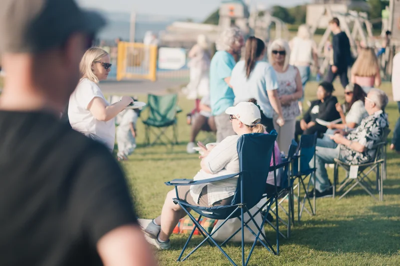 a group of people sitting on lawn chairs in a grassy area