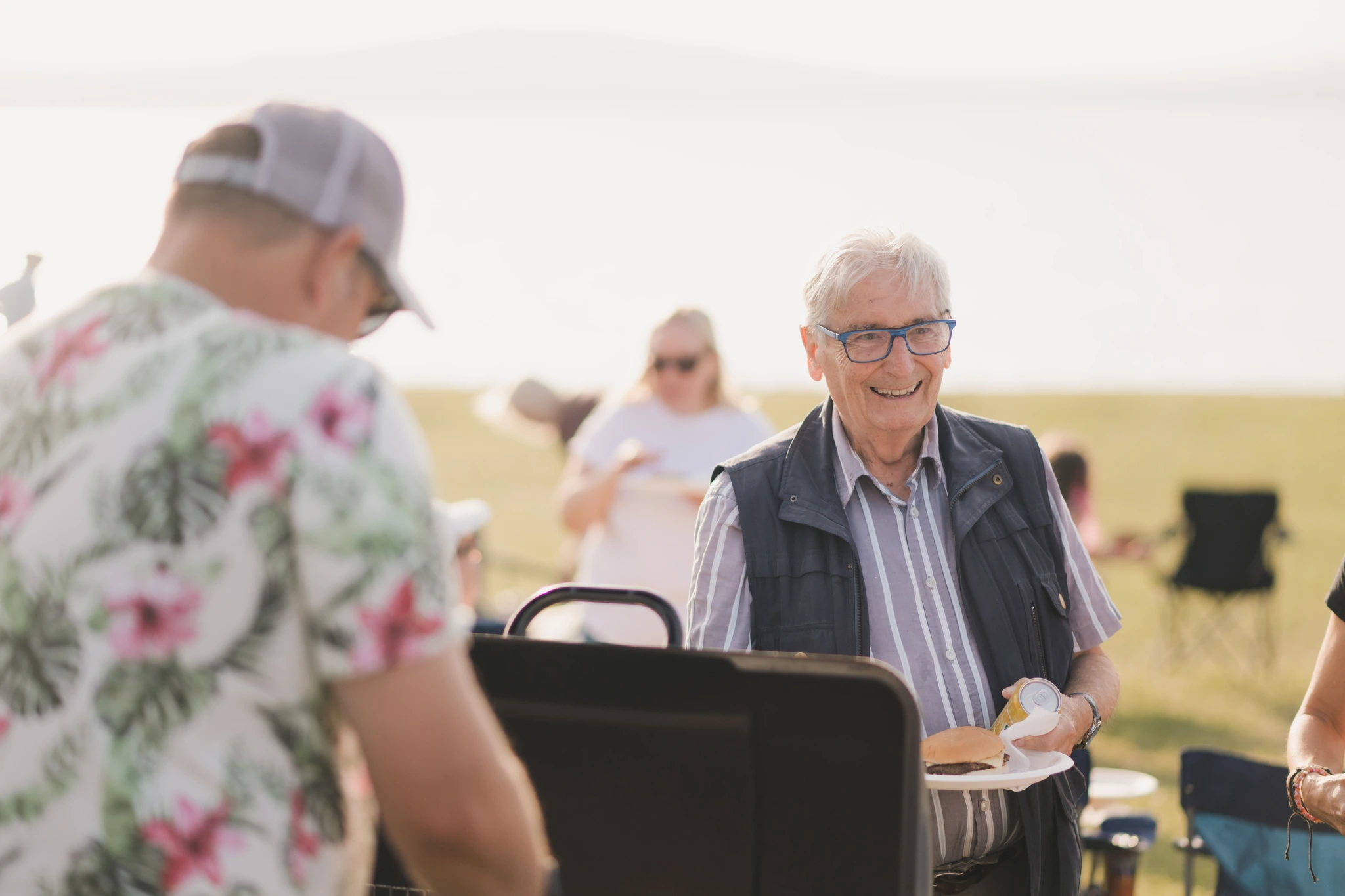 a group of elderly people enjoying a barbecue at a park