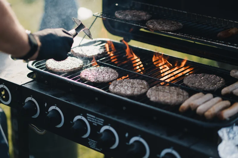 a man grilling burgers on a barbecue grill