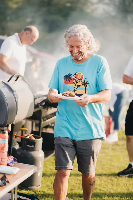 a man with a bbq grill in front of a crowd of people