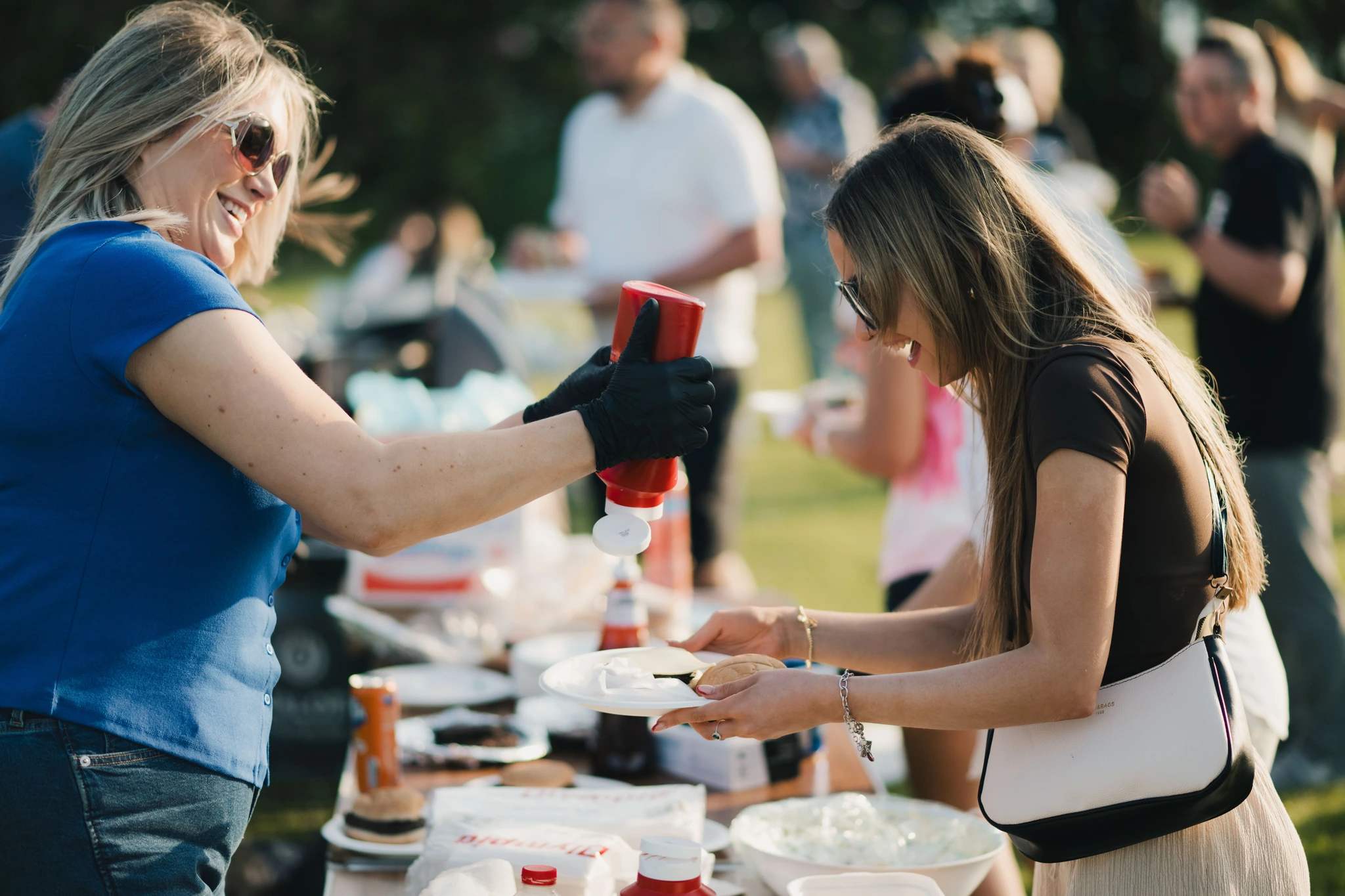 a woman is pouring a drink into a cup at an outdoor event