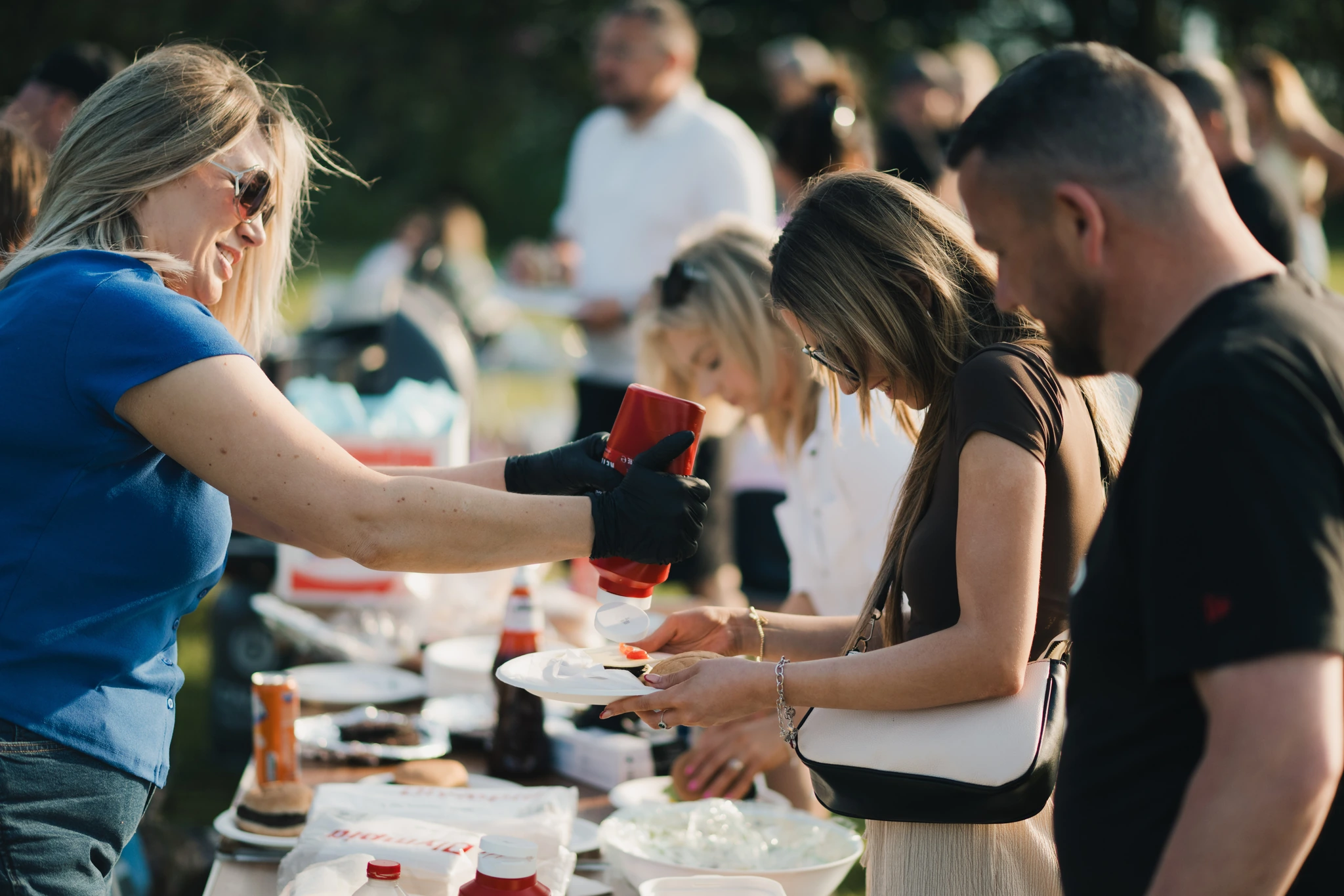 a group of people serving food to a crowd of people at an outdoor event
