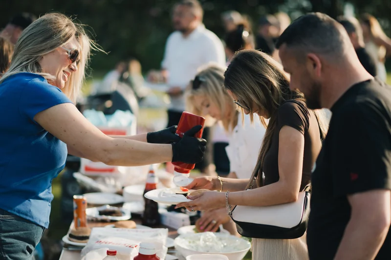 a group of people serving food to a crowd of people at an outdoor event