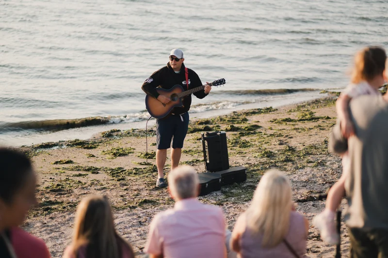 a man playing an acoustic guitar on the beach