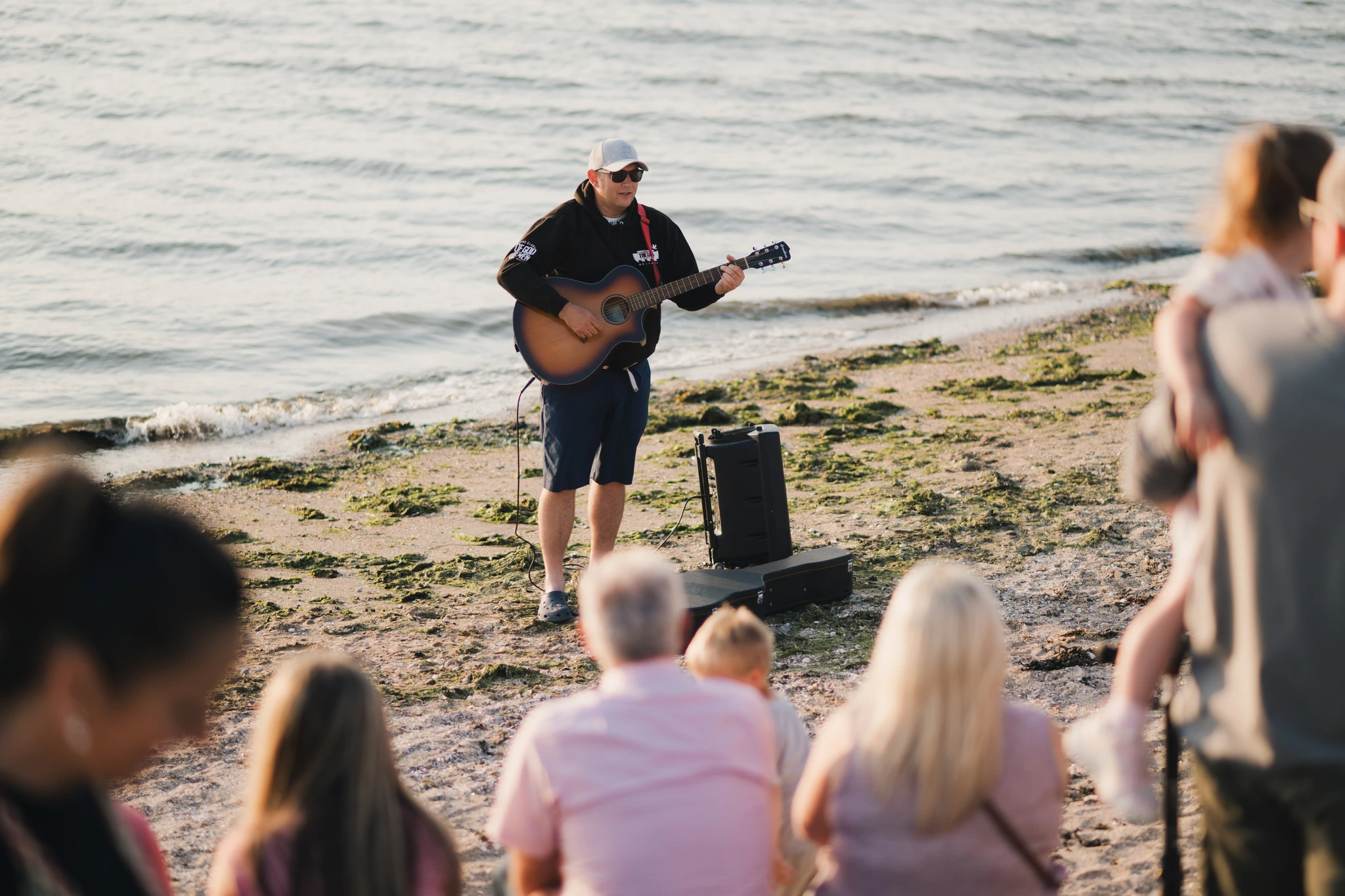 a man playing an acoustic guitar on the beach