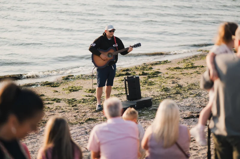 a man playing an acoustic guitar on the beach