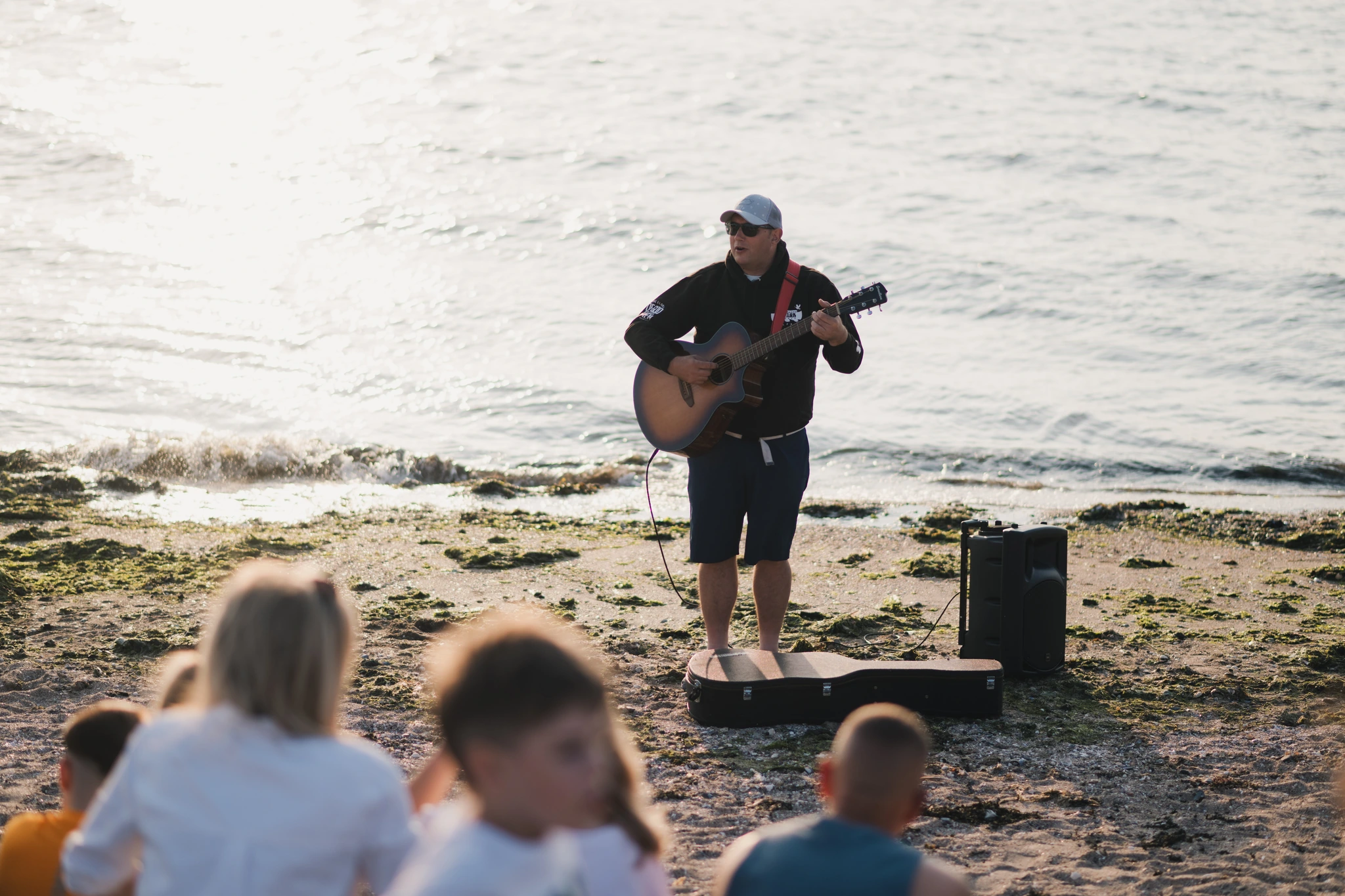 a man playing an acoustic guitar on the beach