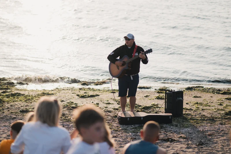 a man playing an acoustic guitar on the beach