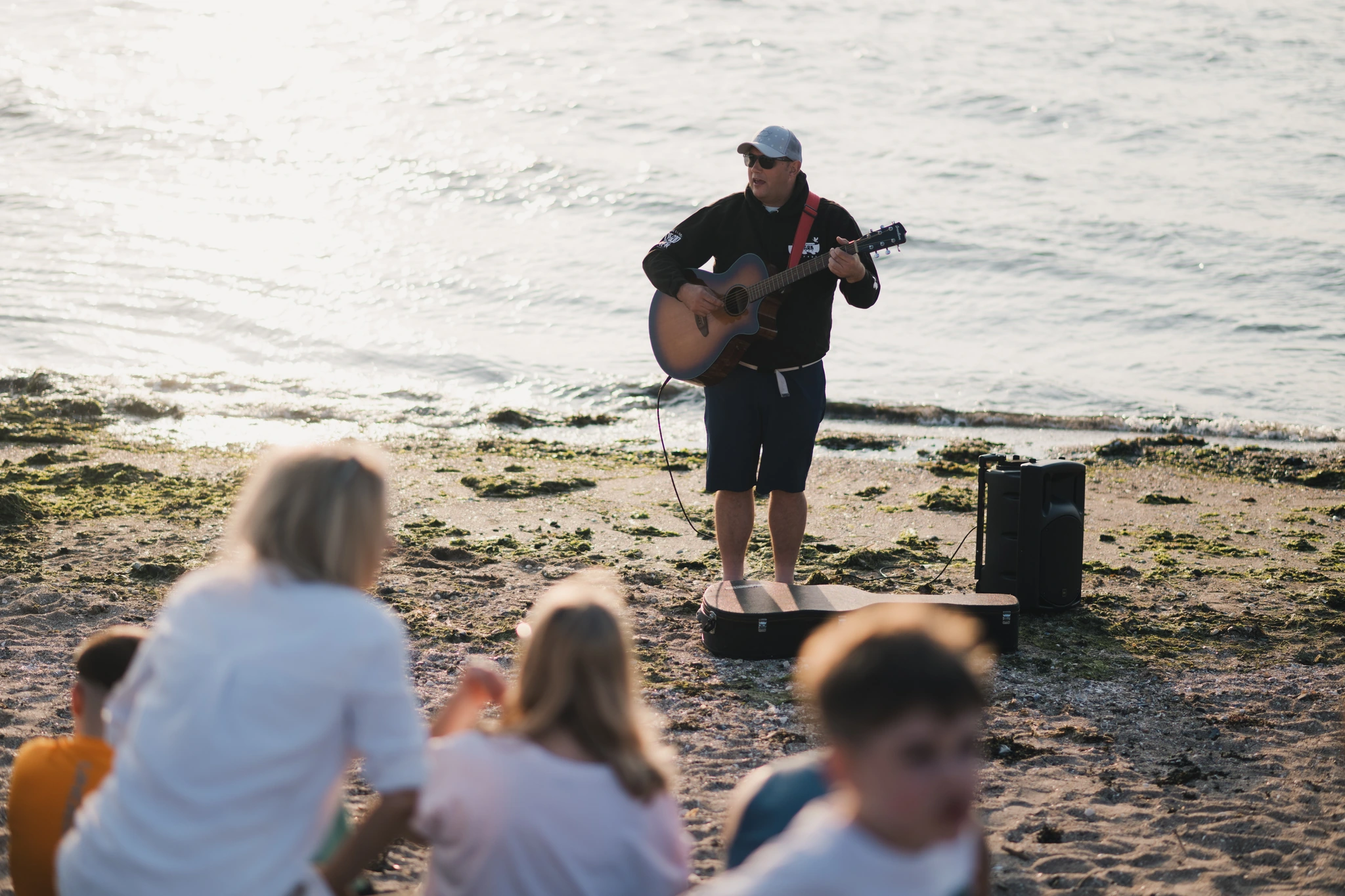 a man playing an acoustic guitar on the beach