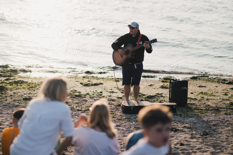 a man playing an acoustic guitar on the beach