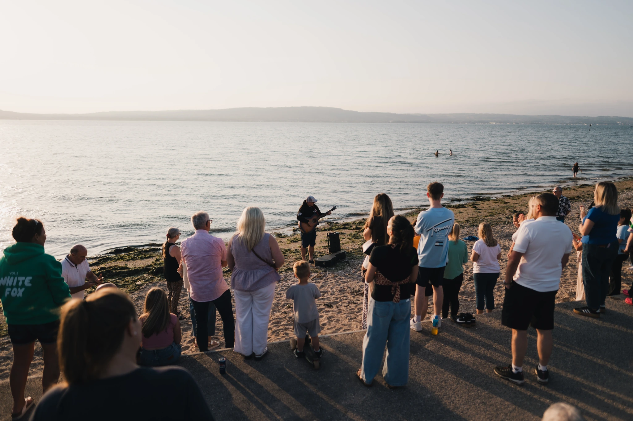 a group of people watching a sunset on a beach