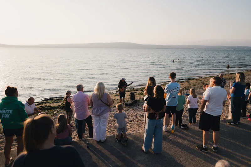 a group of people watching a sunset on a beach