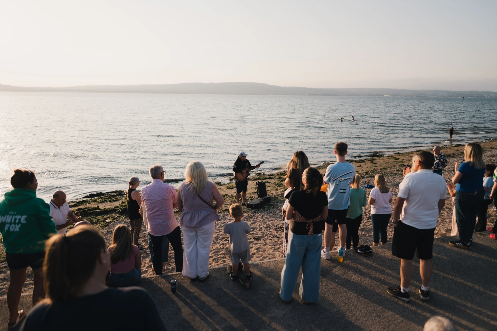 a group of people standing on a beach watching the sunset