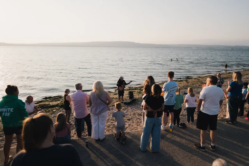a group of people standing on a beach watching the sunset