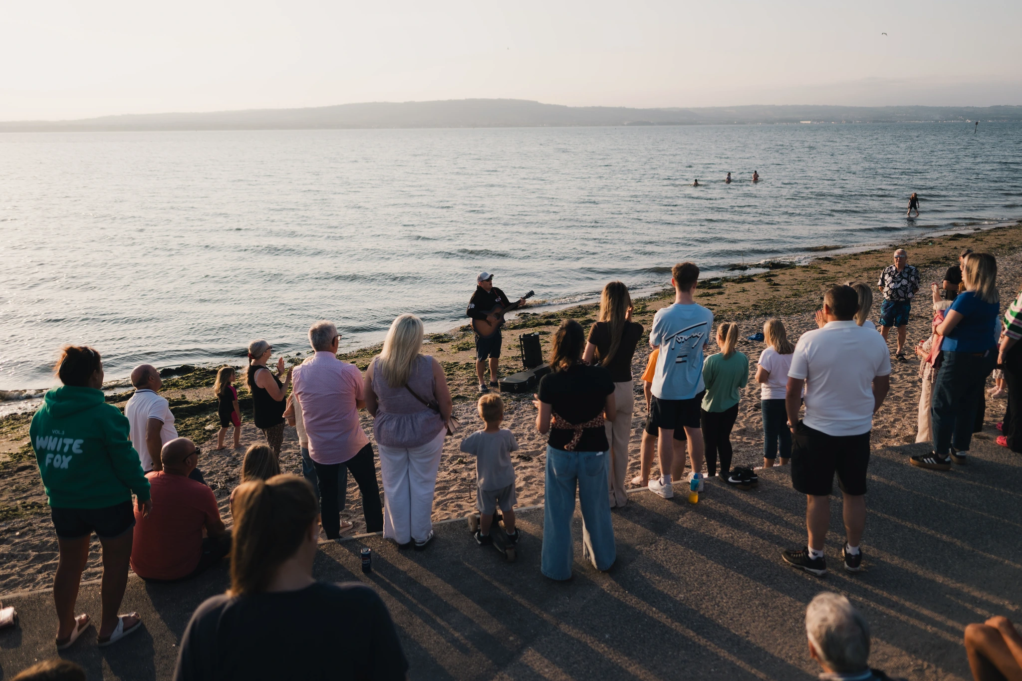 a group of people standing on a beach watching the sunset