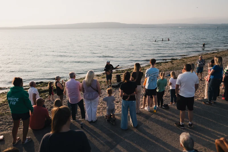 a group of people standing on a beach watching the sunset