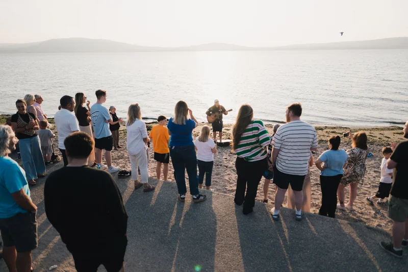 a group of people standing in front of a lake or river