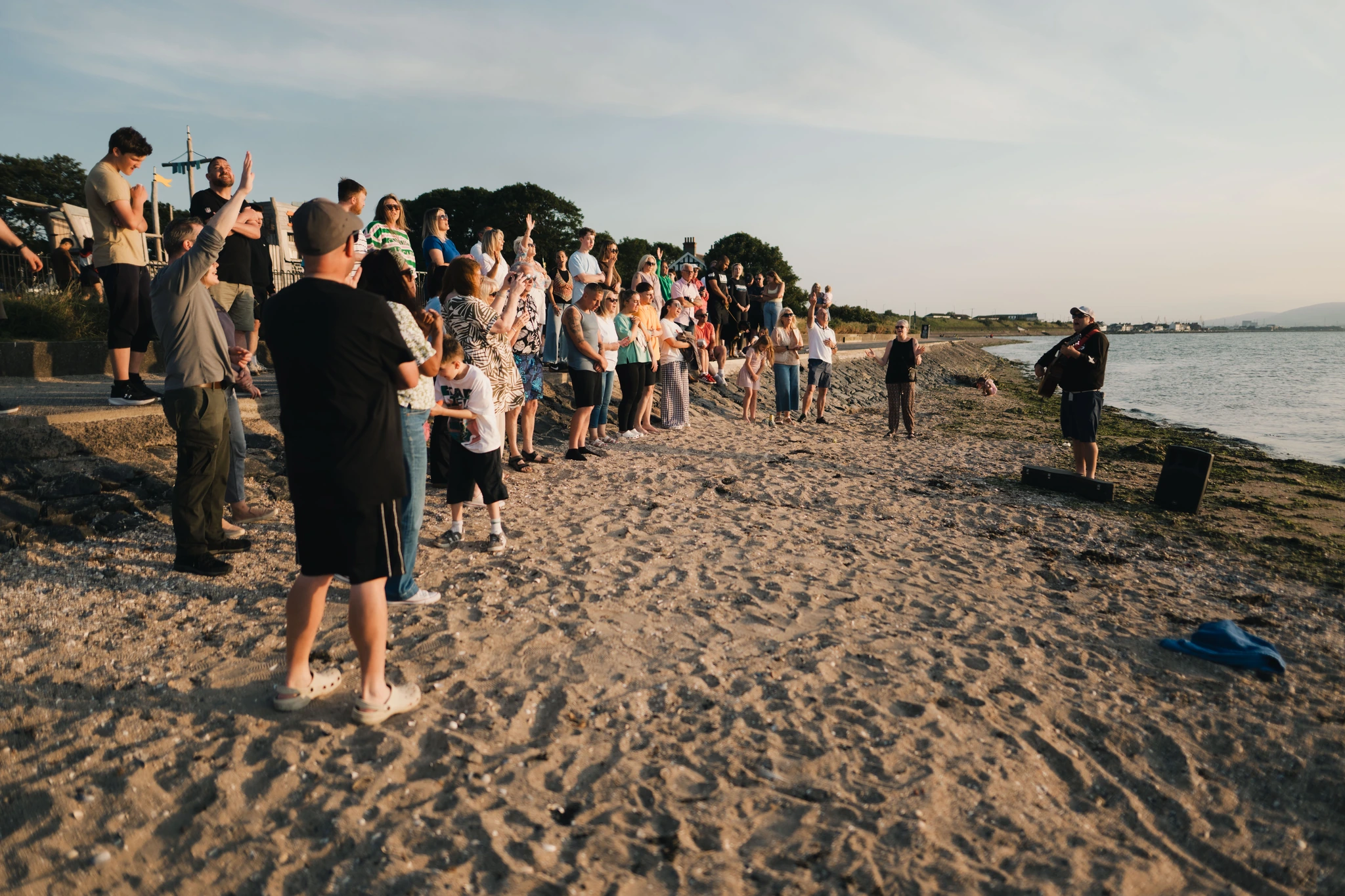 a group of people standing on a beach watching a sunset