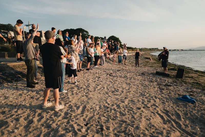 a group of people standing on a beach watching a sunset