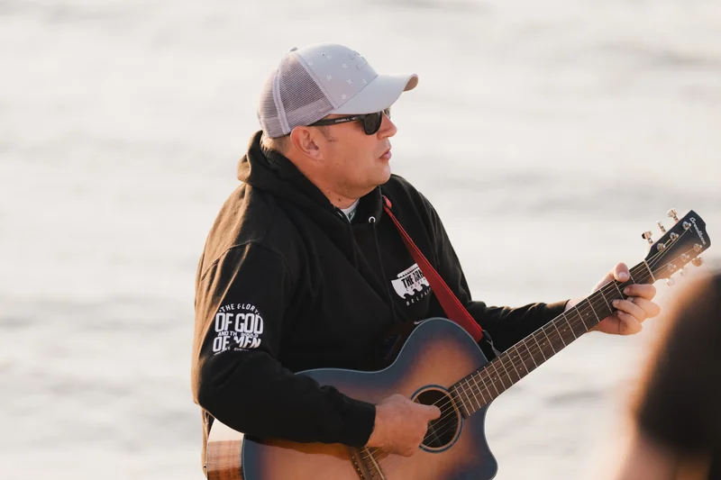 a man plays an acoustic guitar on the beach