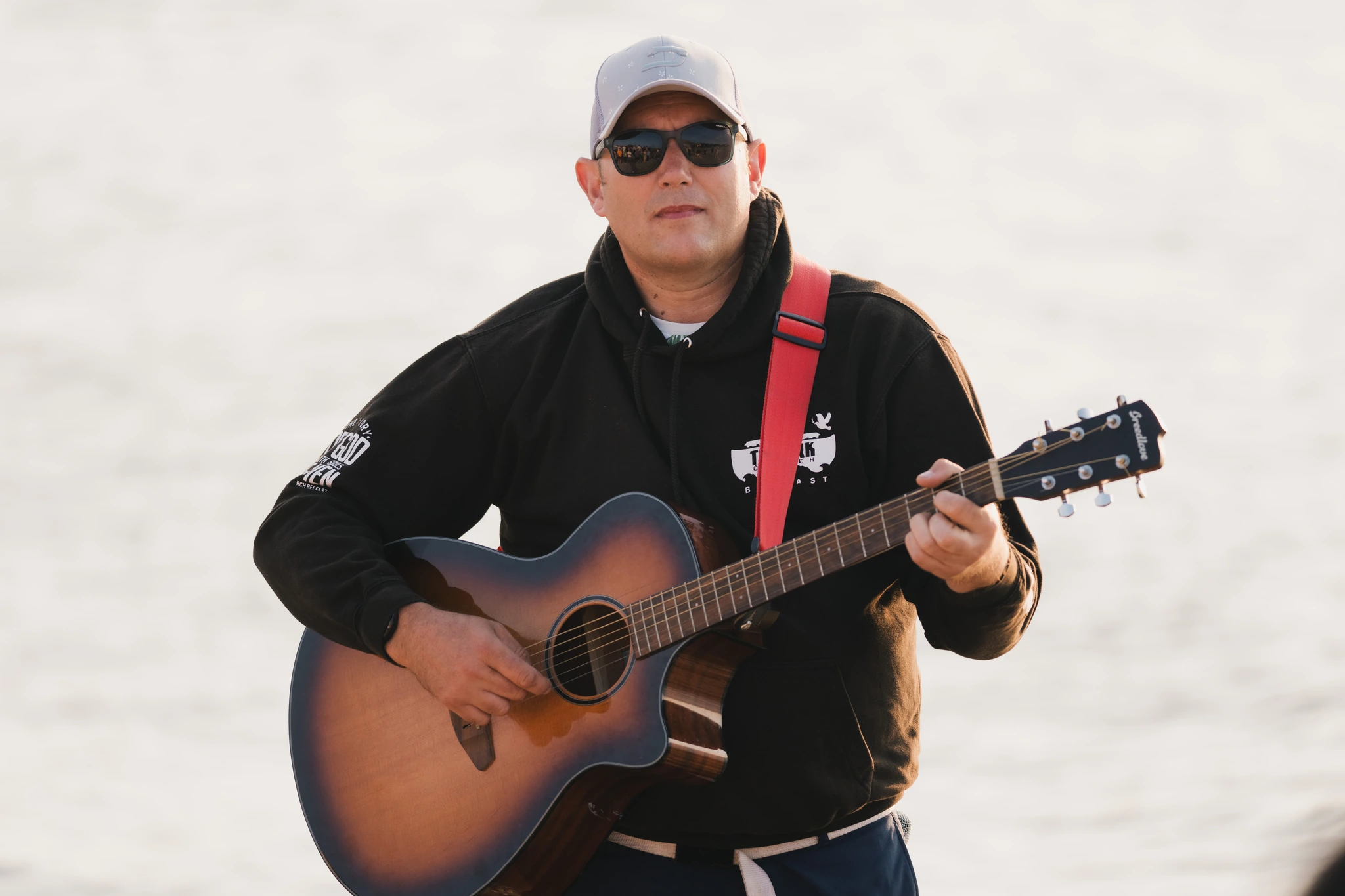 a man in sunglasses plays an acoustic guitar