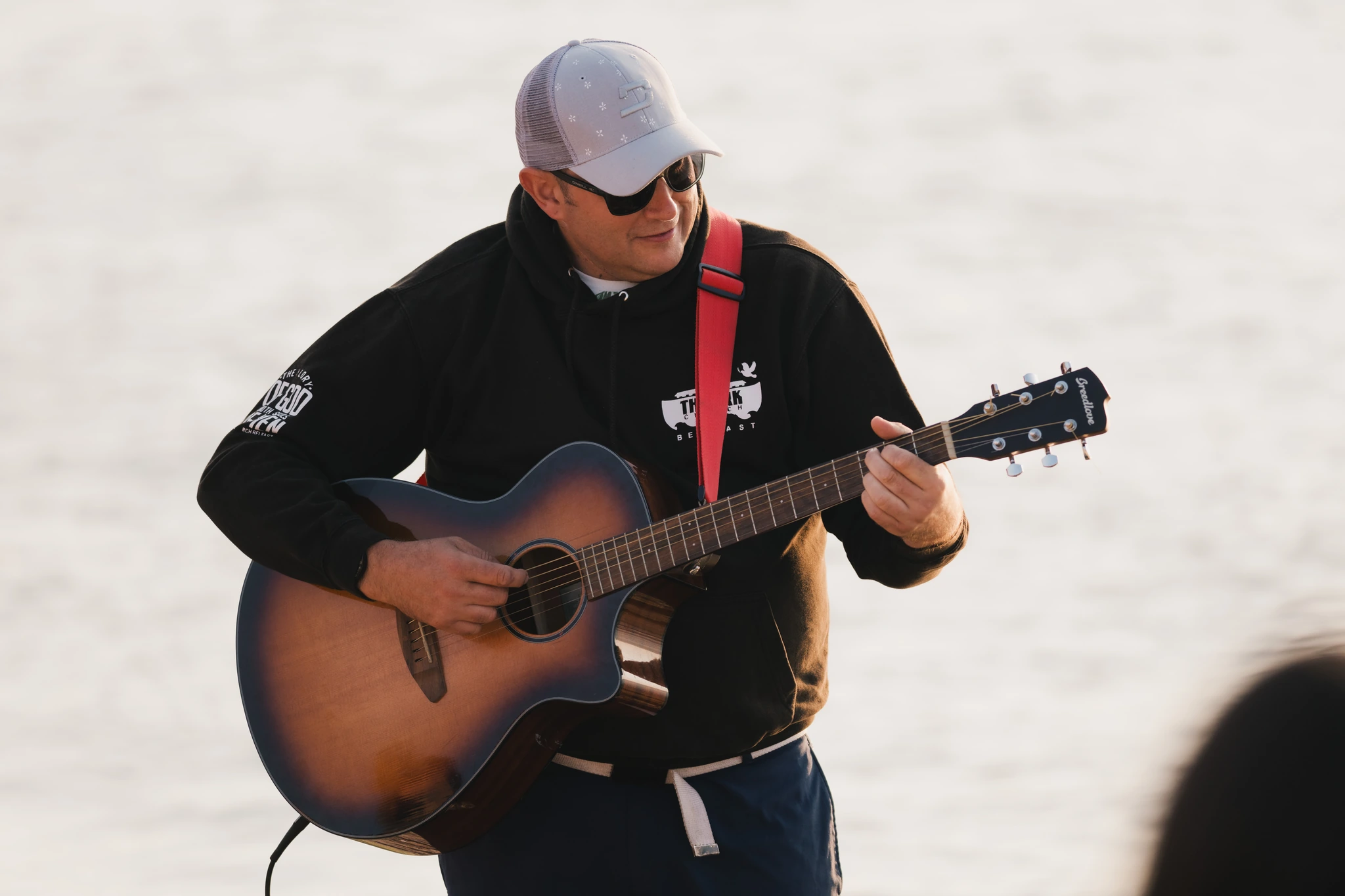 a man plays an acoustic guitar in front of a crowd