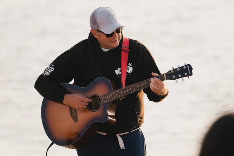 a man plays an acoustic guitar in front of a crowd