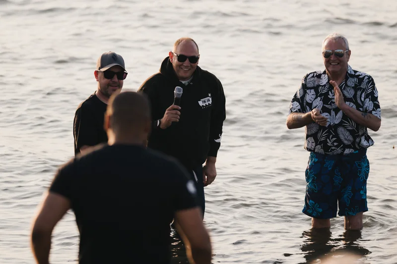 three men standing in the water with a microphone in their hands