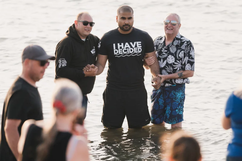 a group of people standing in the water with their hands in the air