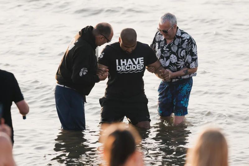 a group of men and women are standing in the water with a sign saying have a blessed day
