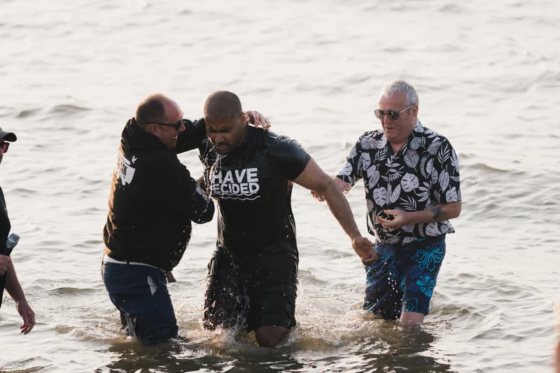 a group of men and women stand in the water as they are baptized
