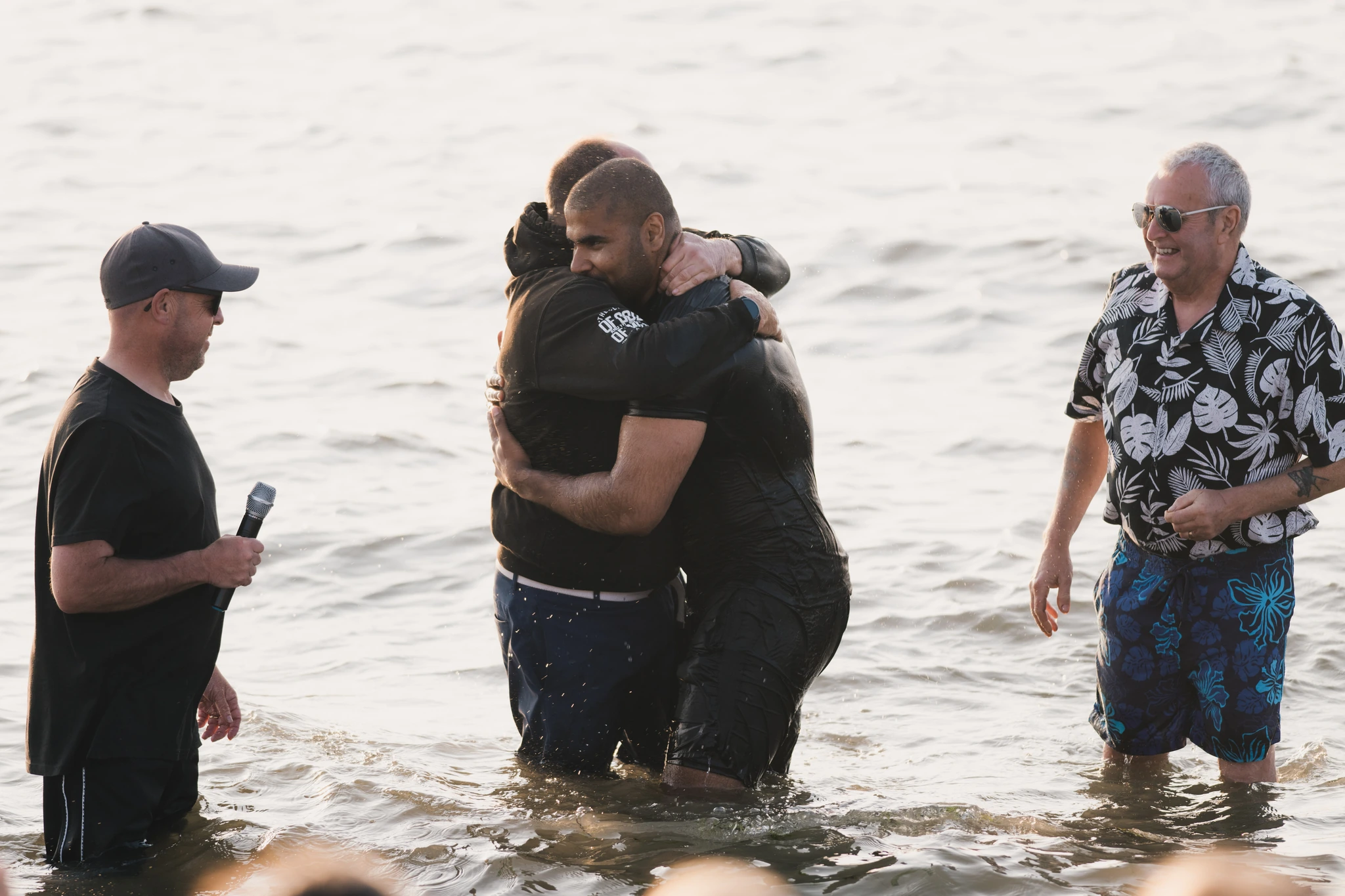 a man in the water with a woman standing behind him in front of a crowd of people