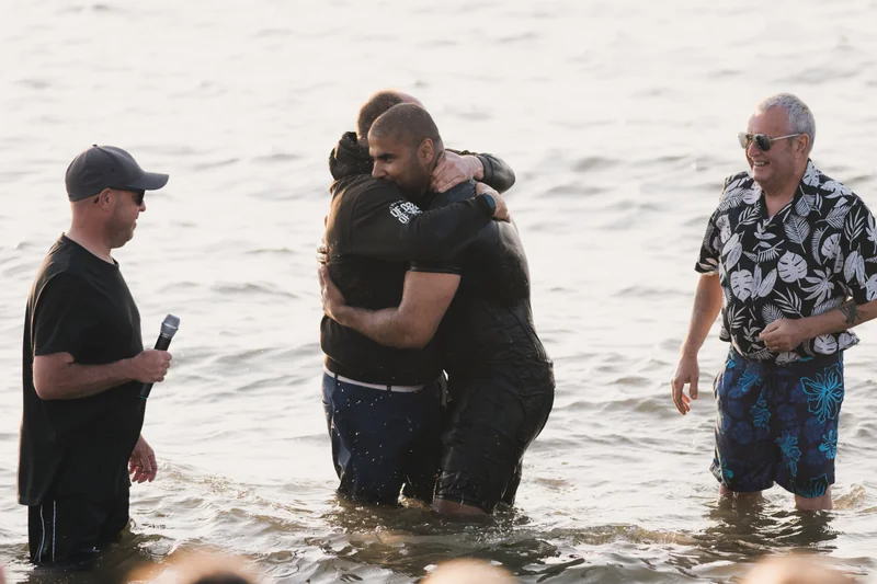 a man in the water with a woman standing behind him in front of a crowd of people