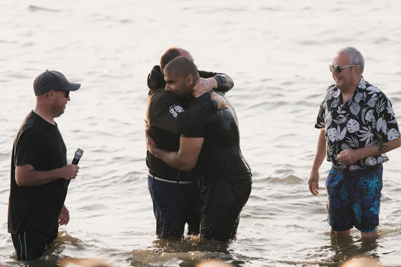 a man in the water with a group of people standing around him