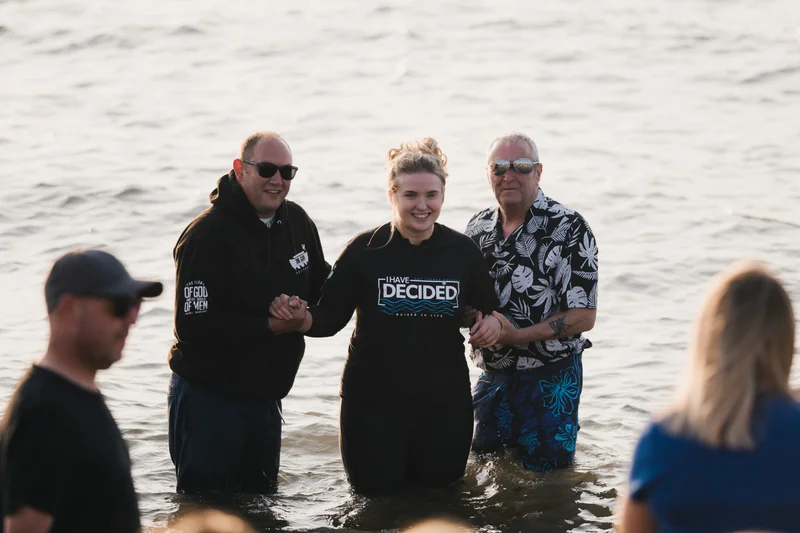 a group of people standing in the water with their hands in the air