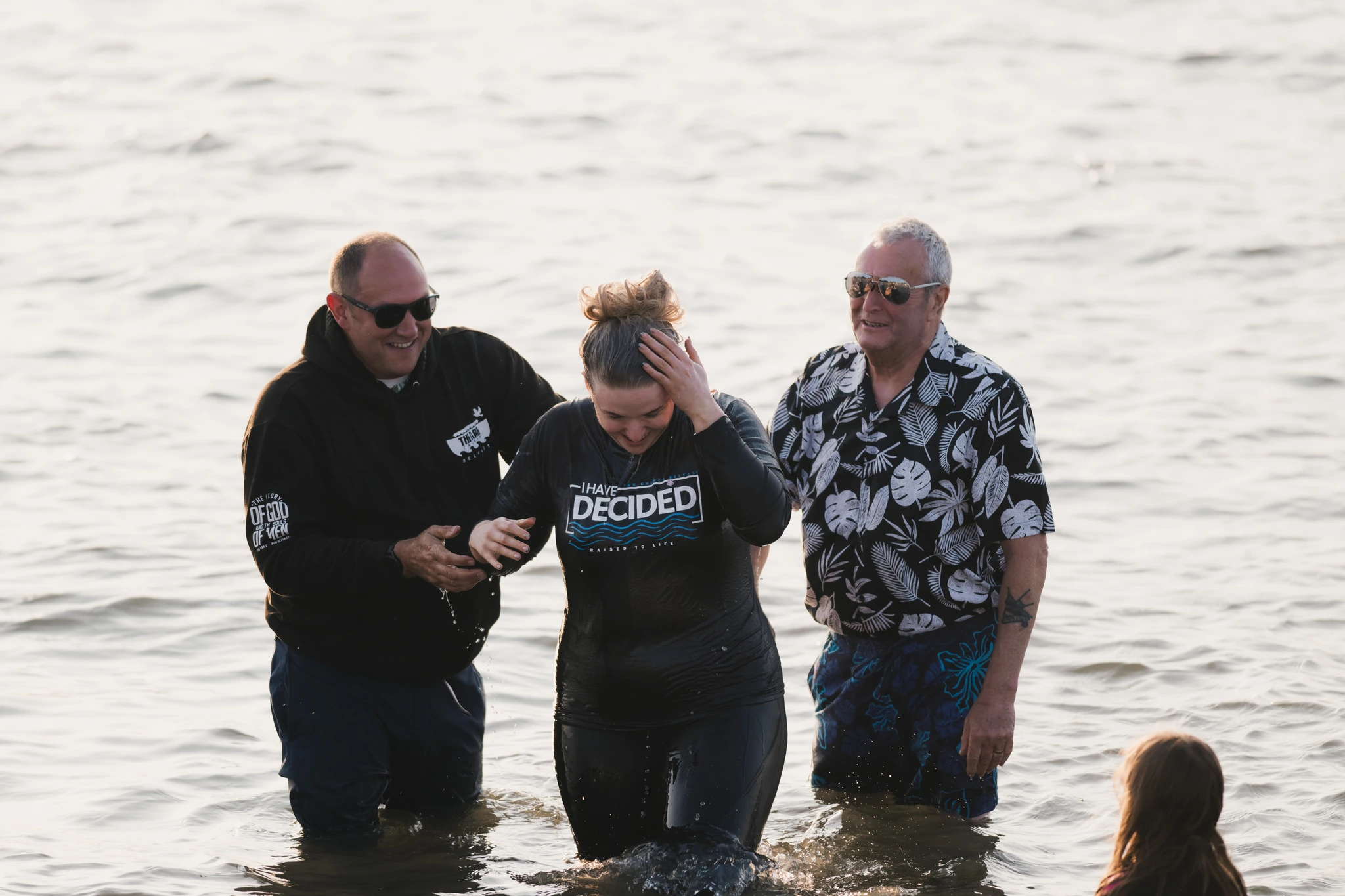a man and woman standing in the water with a baby in their arms