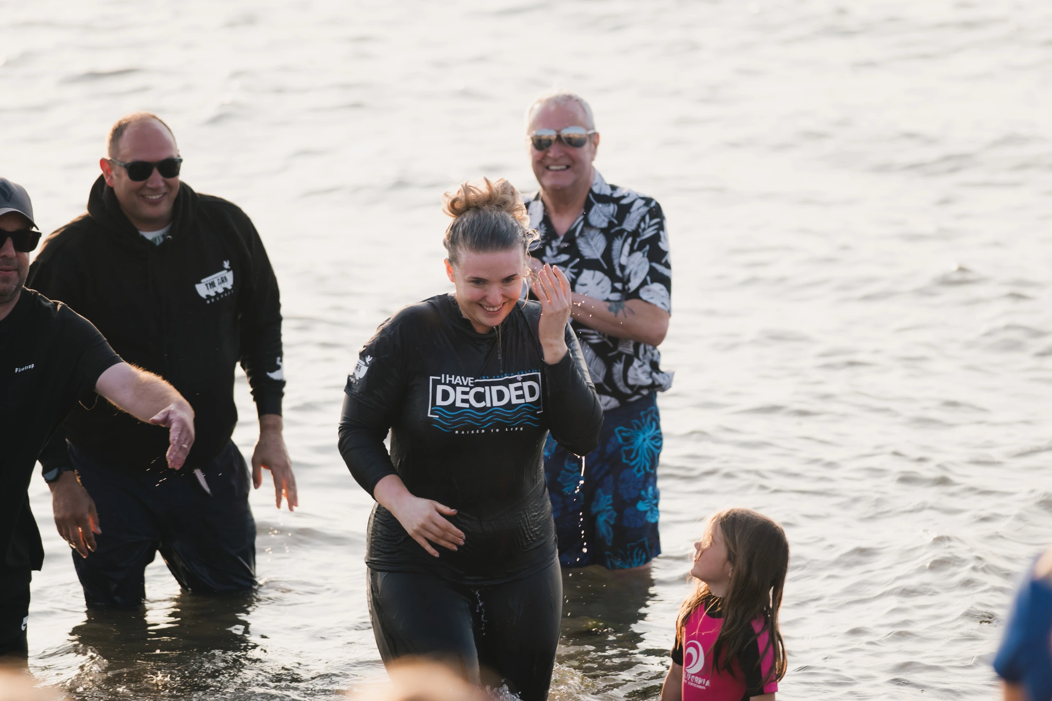 a group of people standing in the water with a child in front of them