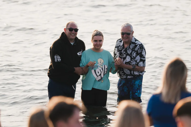 a man and woman standing next to a group of people in the water