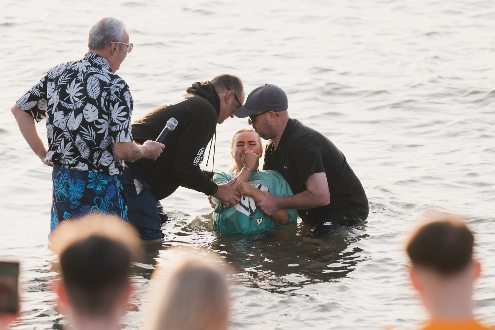 christian baptism in the water by a man in front of a group of people