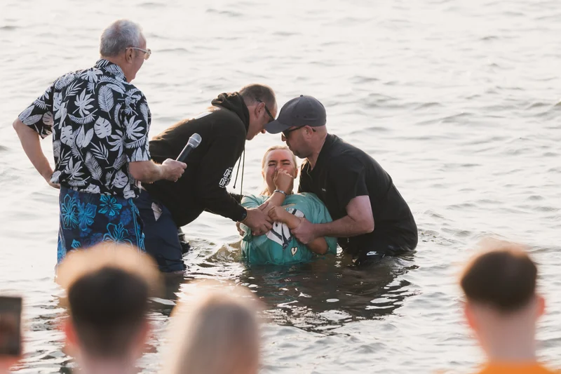 christian baptism in the water by a man in front of a group of people