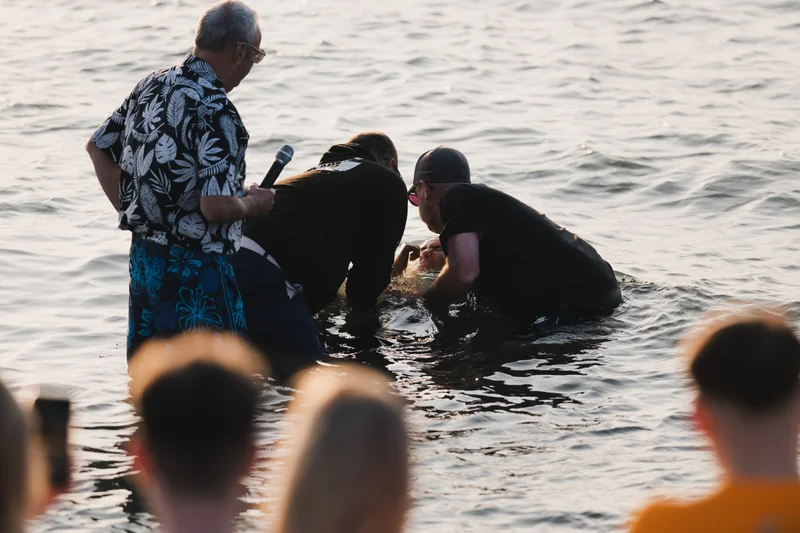 a group of people standing in the water with a man in front of them