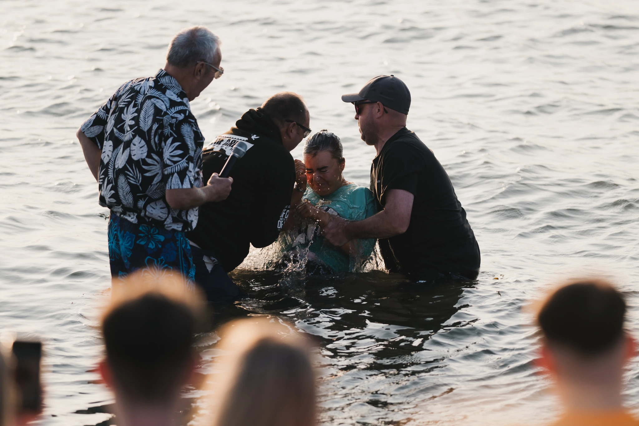 a group of people standing in the water with a man in front of them