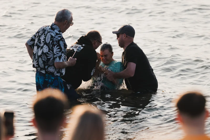 a group of people standing in the water with a man in front of them