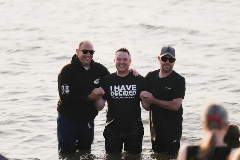 a group of men and women standing in the water with a sign that says have a good day